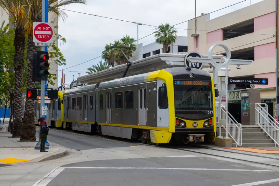 A light rail train waits at the Downtown Long Beach station with a sign that reads “Long Beach” to declare its route to riders.